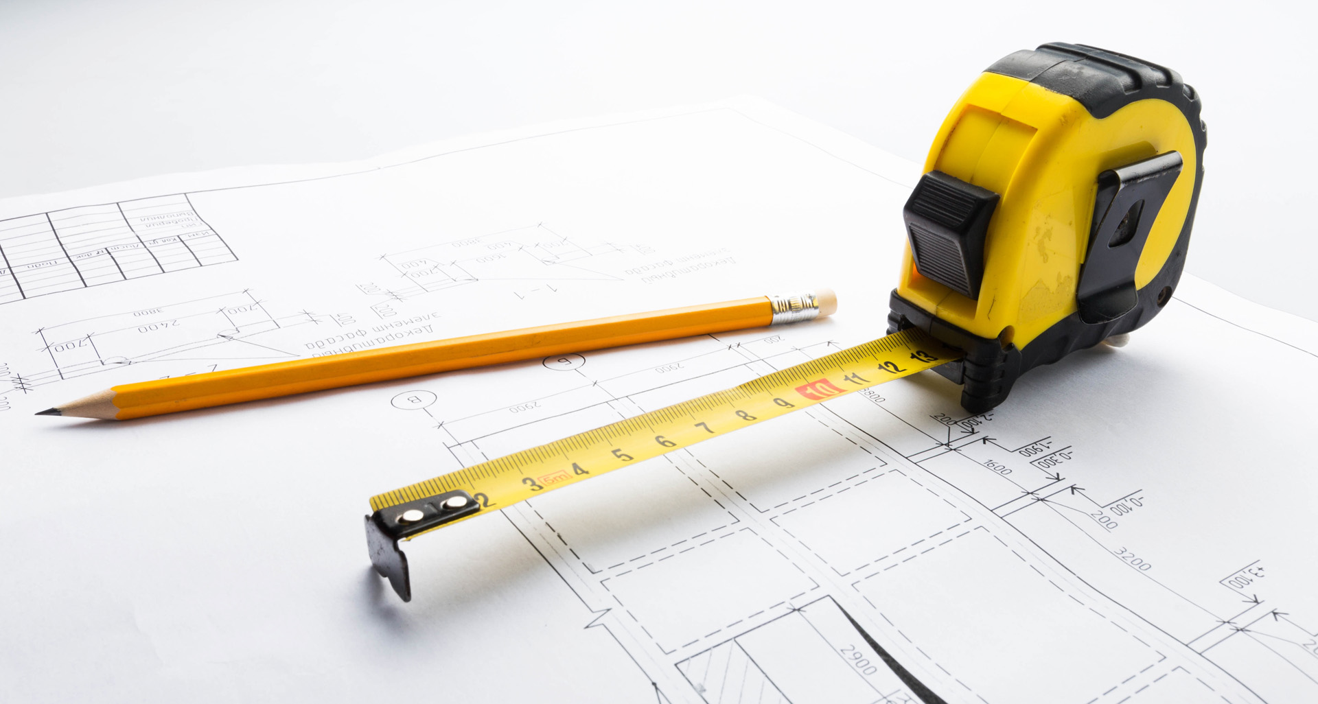 Mètre ruban et crayon sur un plan pour calculer le volume de béton d'un chantier